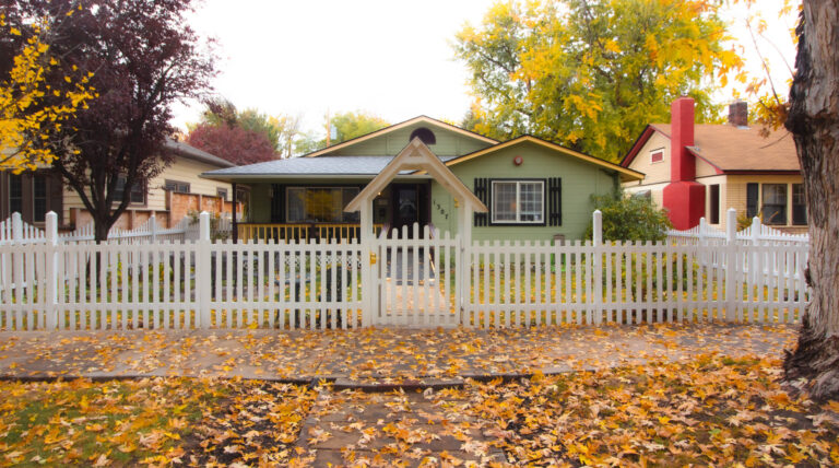 Assisted living home, white picket fence and multicolored leaves all around.